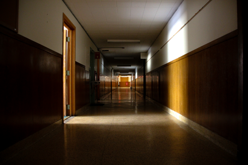 An dark empty school hallway with light coming in from a classroom